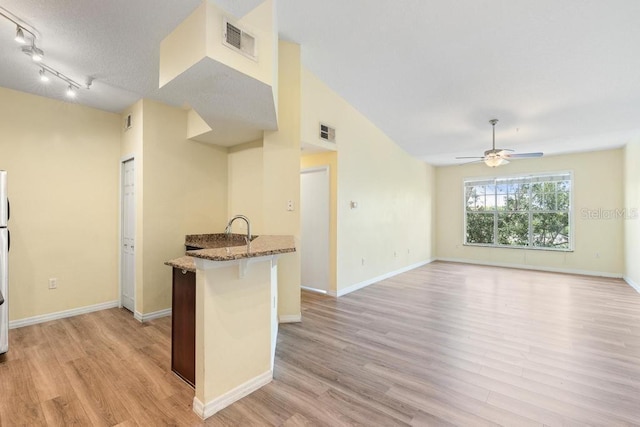 5518 Metrowest Blvd Unit 11-302, Orlando, FL 32811 - kitchen with stone counters, light wood-style floors, a ceiling fan, a kitchen bar, and a peninsula