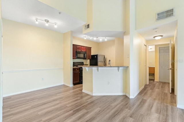 5518 Metrowest Blvd Unit 11-302, Orlando, FL 32811 - kitchen with freestanding refrigerator, electric range oven, black microwave, light wood-type flooring, and a kitchen breakfast bar