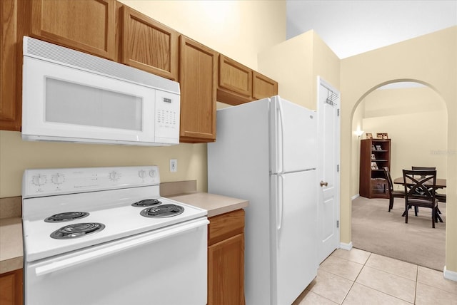 637 Harbor Villa Ct, Clermont, FL 34711 - kitchen featuring white appliances, arched walkways, light colored carpet, light countertops, and light tile patterned floors