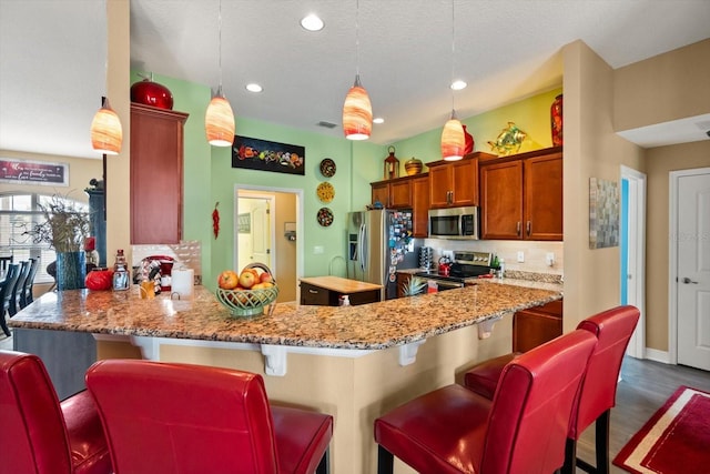 406 Benjamin Ct, Fruitland Park, FL 34731 - kitchen featuring appliances with stainless steel finishes, brown cabinets, decorative backsplash, a peninsula, and a kitchen breakfast bar