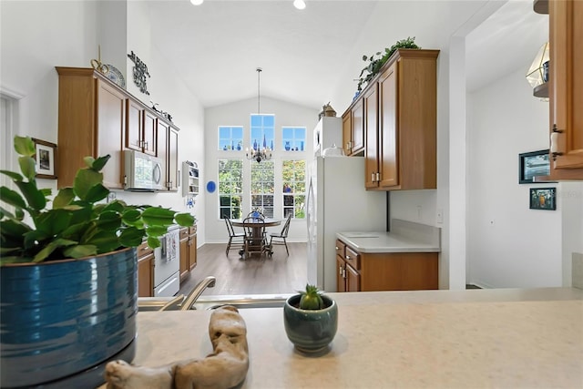 5135 Indian Ocean Loop, Tavares, FL 32778 - kitchen featuring white appliances, brown cabinetry, lofted ceiling, a chandelier, and dark wood-style floors