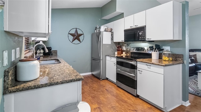 11746 Oswalt Rd, Clermont, FL 34711 - kitchen featuring stainless steel appliances, white cabinets, light wood-style flooring, and dark stone countertops