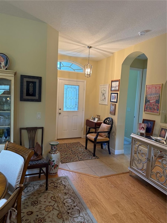 8301 Bridgeport Bay Cir, Mount Dora, FL 32757 - foyer entrance with arched walkways, a textured ceiling, a chandelier, and light wood-style flooring