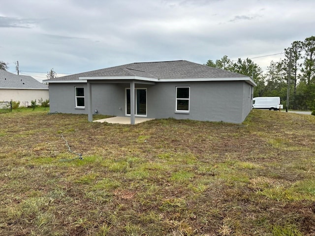3838 W Baton Ln, Citrus Springs, FL 34433 - rear view of property featuring a patio, stucco siding, roof with shingles, and a lawn