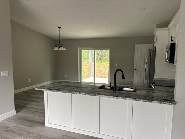 3838 W Baton Ln, Citrus Springs, FL 34433 - kitchen featuring stainless steel appliances, dark stone countertops, white cabinetry, a peninsula, and wood finished floors