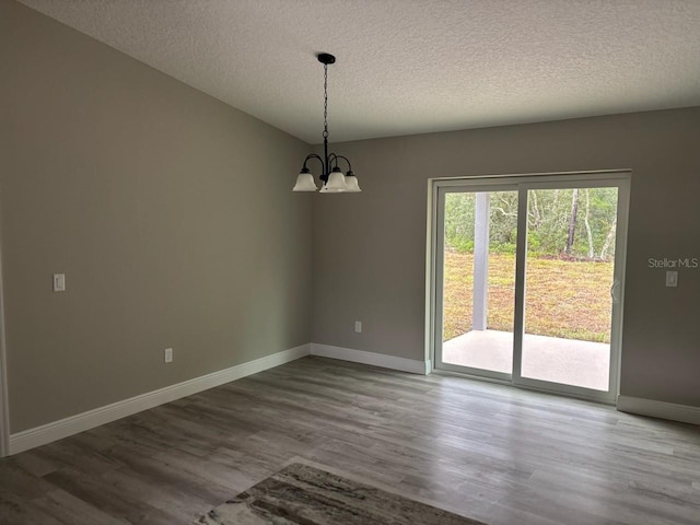 3838 W Baton Ln, Citrus Springs, FL 34433 - empty room featuring a textured ceiling, a chandelier, and wood finished floors