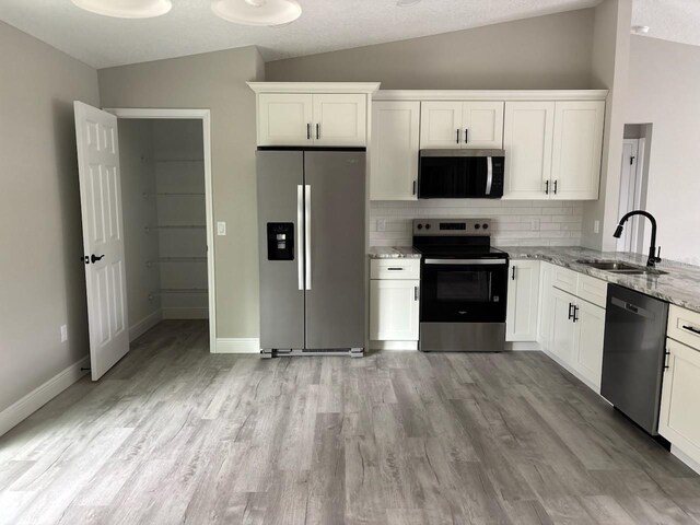3838 W Baton Ln, Citrus Springs, FL 34433 - kitchen featuring stainless steel appliances, lofted ceiling, decorative backsplash, light stone counters, and light wood-style floors