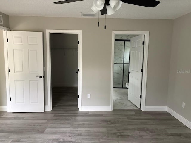3838 W Baton Ln, Citrus Springs, FL 34433 - unfurnished bedroom with a spacious closet, ensuite bathroom, wood finished floors, and a ceiling fan