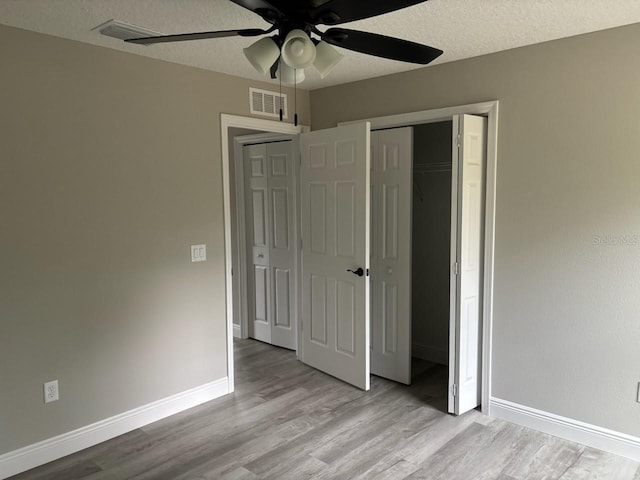 3838 W Baton Ln, Citrus Springs, FL 34433 - unfurnished bedroom with light wood-style flooring, a closet, a textured ceiling, and a ceiling fan