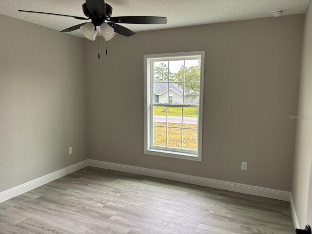 3838 W Baton Ln, Citrus Springs, FL 34433 - unfurnished room featuring light wood-style flooring, ceiling fan, a smoke detector, and a textured ceiling