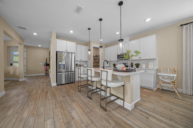 3916 Southern Vista Loop, Saint Cloud, FL 34772 - kitchen featuring stainless steel appliances, light wood-style flooring, light countertops, a breakfast bar, and an island with sink