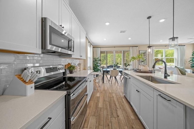 3916 Southern Vista Loop, Saint Cloud, FL 34772 - kitchen featuring appliances with stainless steel finishes, light wood-style flooring, light countertops, white cabinets, and recessed lighting
