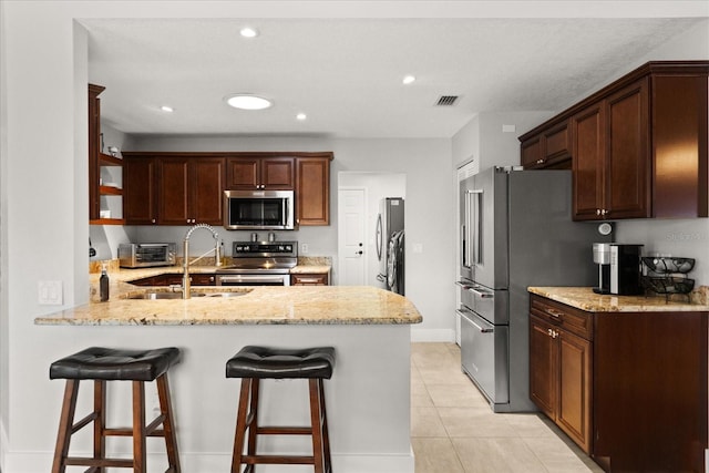 17525 SE 111th Cir, Summerfield, FL 34491 - kitchen with stainless steel appliances, a peninsula, a kitchen breakfast bar, light tile patterned floors, and recessed lighting