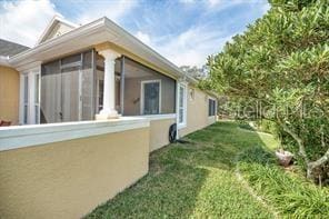 370 Salt Marsh Ln, Groveland, FL 34736 - view of side of home with a sunroom, stucco siding, and a yard
