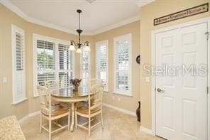 370 Salt Marsh Ln, Groveland, FL 34736 - dining room featuring crown molding, a chandelier, and light tile patterned flooring