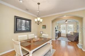 370 Salt Marsh Ln, Groveland, FL 34736 - dining space featuring arched walkways, wood finished floors, crown molding, and a chandelier