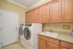370 Salt Marsh Ln, Groveland, FL 34736 - washroom with washing machine and dryer, cabinet space, crown molding, and light tile patterned flooring
