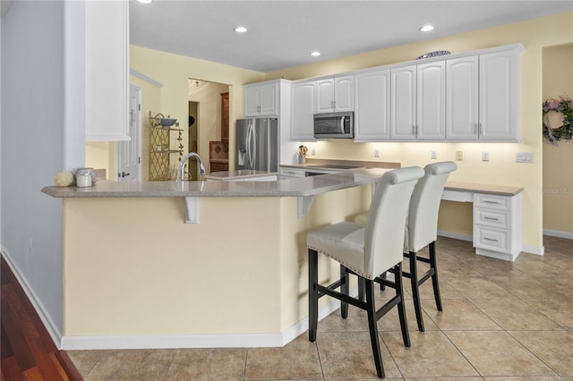 7811 Laurel View Dr, Mount Dora, FL 32757 - kitchen featuring stainless steel appliances, a peninsula, a kitchen breakfast bar, white cabinets, and recessed lighting