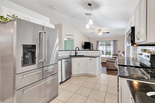 2305 Foxtree Rd, Tavares, FL 32778 - kitchen with stainless steel appliances, a peninsula, vaulted ceiling, decorative backsplash, and white cabinets