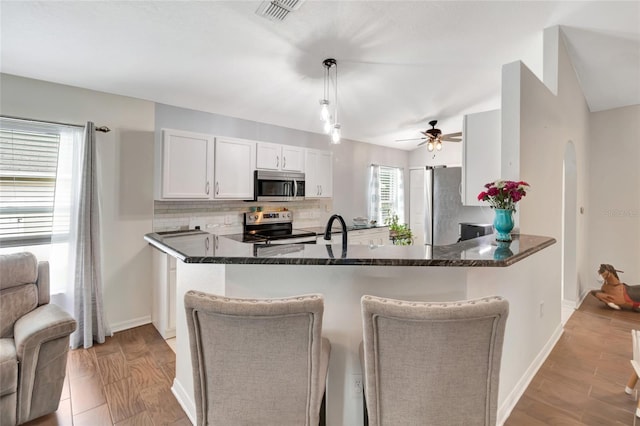 2305 Foxtree Rd, Tavares, FL 32778 - kitchen featuring appliances with stainless steel finishes, a ceiling fan, tasteful backsplash, a peninsula, and a kitchen bar