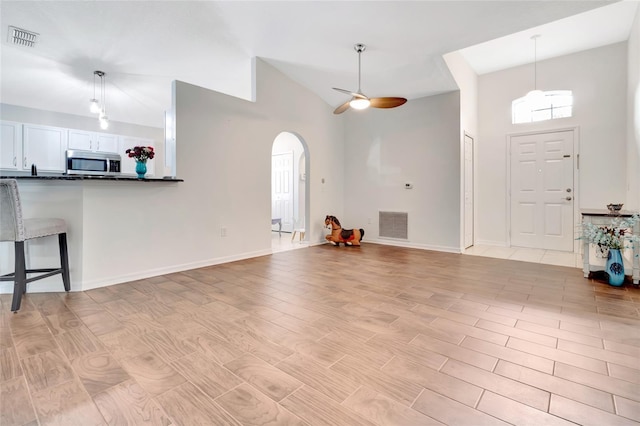 2305 Foxtree Rd, Tavares, FL 32778 - unfurnished living room featuring arched walkways, high vaulted ceiling, a ceiling fan, and light wood-style flooring