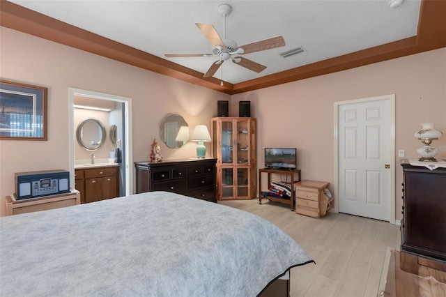 6307 Berkshire Pass, Leesburg, FL 34748 - bedroom featuring light wood-style flooring, connected bathroom, ceiling fan, and a raised ceiling