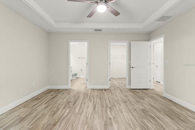 671 E Toledo Dr, Citrus Springs, FL 34434 - unfurnished bedroom with a raised ceiling, light wood finished floors, a walk in closet, ensuite bath, and a ceiling fan