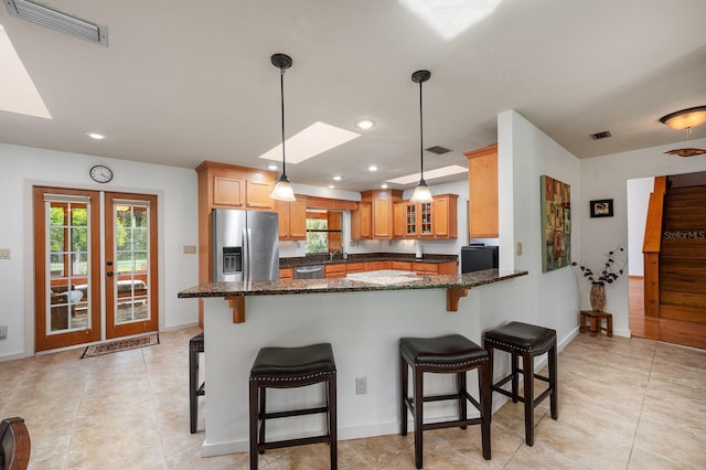 7201 SW 97th Ln, Gainesville, FL 32608 - kitchen with stainless steel refrigerator with ice dispenser, a skylight, a peninsula, glass insert cabinets, and a kitchen bar