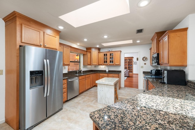 7201 SW 97th Ln, Gainesville, FL 32608 - kitchen with appliances with stainless steel finishes, a skylight, dark stone countertops, a center island, and recessed lighting