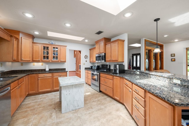 7201 SW 97th Ln, Gainesville, FL 32608 - kitchen featuring appliances with stainless steel finishes, a skylight, glass insert cabinets, dark stone countertops, and recessed lighting
