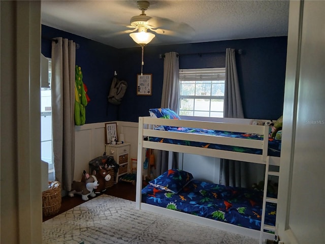309 N Westwood St, Bushnell, FL 33513 - bedroom with a ceiling fan, a textured ceiling, and wainscoting