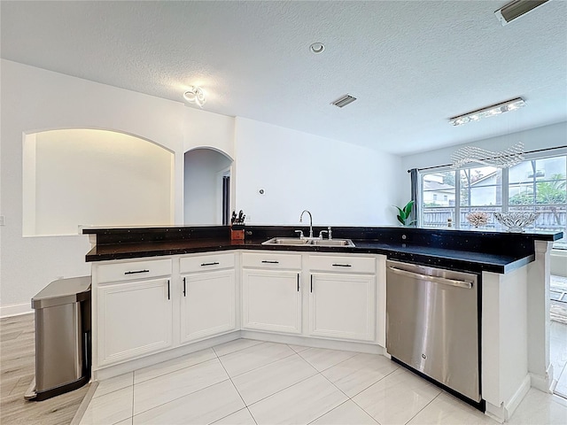 2421 Cimmaron Ash Way, Apopka, FL 32703 - kitchen with dishwasher, arched walkways, a textured ceiling, dark countertops, and white cabinetry