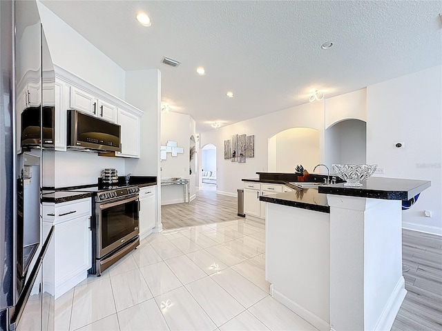 2421 Cimmaron Ash Way, Apopka, FL 32703 - kitchen with electric stove, arched walkways, refrigerator, dark countertops, and white cabinetry