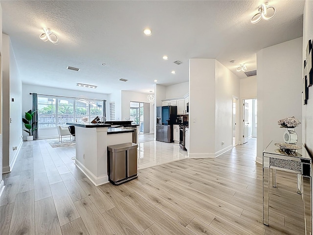 2421 Cimmaron Ash Way, Apopka, FL 32703 - kitchen with plenty of natural light, dark countertops, light wood-style floors, a textured ceiling, and recessed lighting