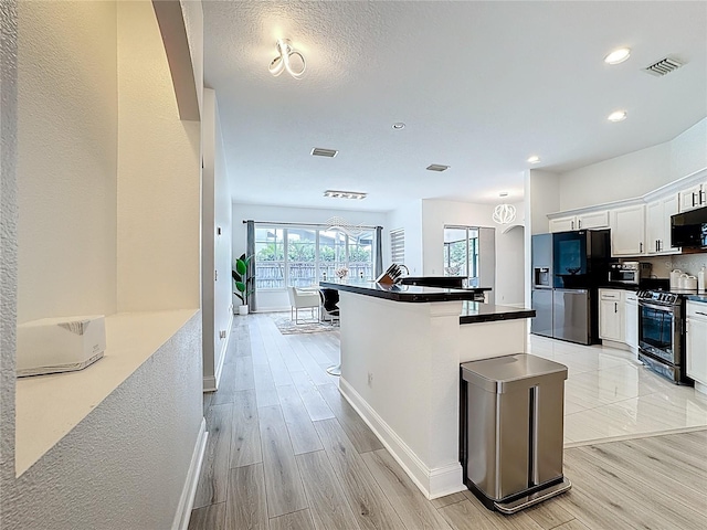 2421 Cimmaron Ash Way, Apopka, FL 32703 - kitchen featuring black appliances, white cabinets, light wood finished floors, dark countertops, and an island with sink