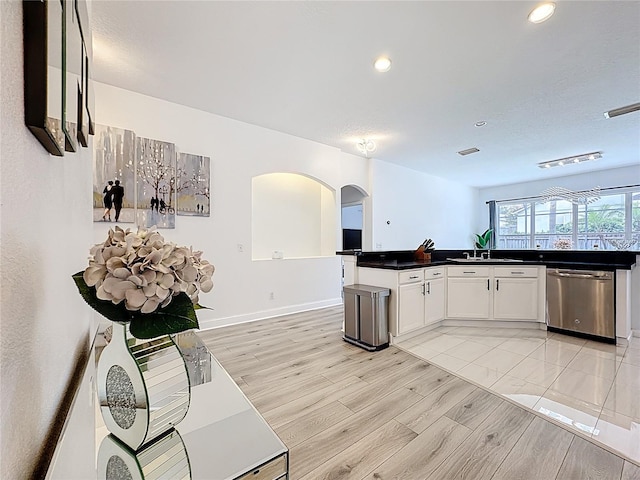 2421 Cimmaron Ash Way, Apopka, FL 32703 - kitchen with stainless steel dishwasher, arched walkways, dark countertops, white cabinetry, and light wood finished floors