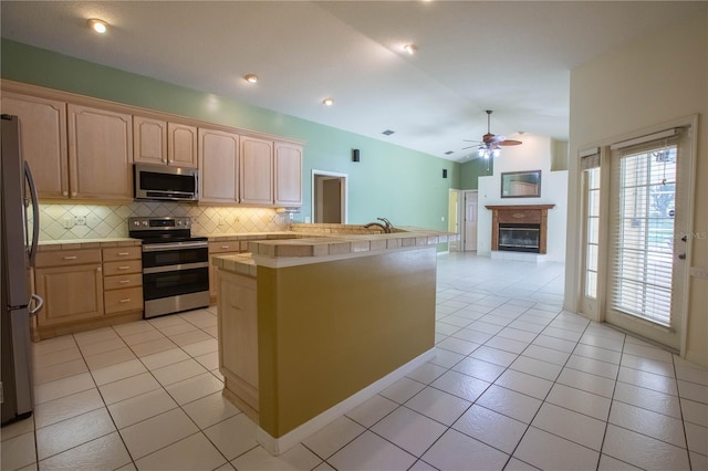 14933 Thoroughbred Ln, Montverde, FL 34756 - kitchen featuring stainless steel appliances, light brown cabinetry, lofted ceiling, light tile patterned floors, and tasteful backsplash