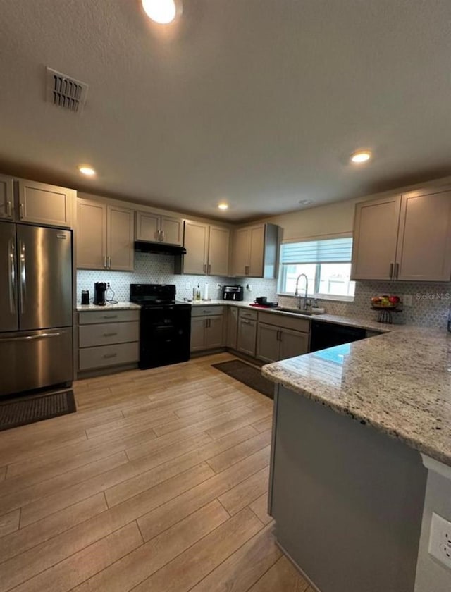 594 Preserve Pt, Davenport, FL 33837 - kitchen with freestanding refrigerator, black / electric stove, gray cabinetry, light stone counters, and decorative backsplash