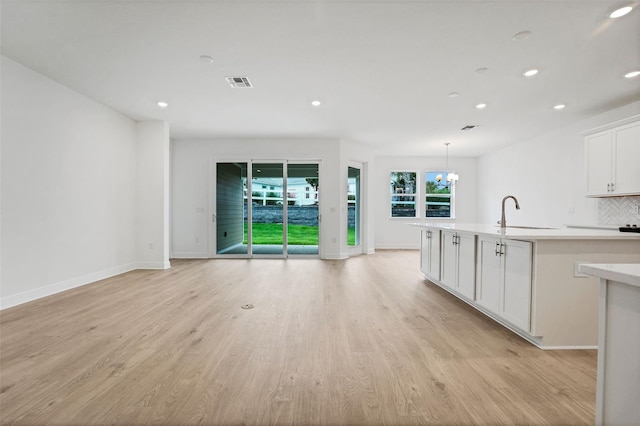 991 Fiesta Key Cir, Lady Lake, FL 32159 - kitchen featuring recessed lighting, a center island with sink, tasteful backsplash, light countertops, and white cabinets