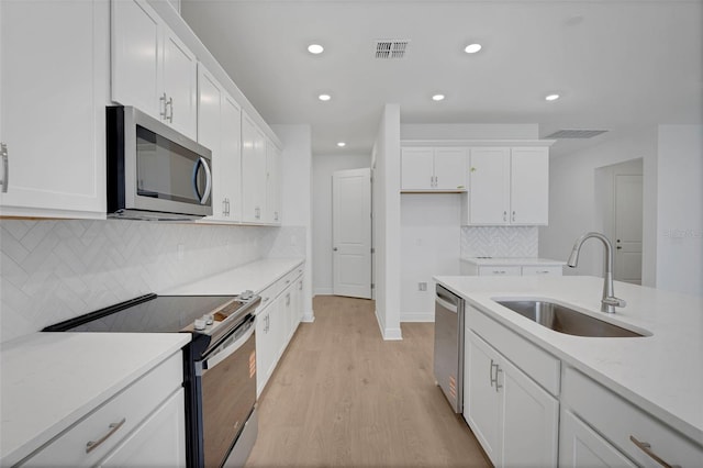991 Fiesta Key Cir, Lady Lake, FL 32159 - kitchen with appliances with stainless steel finishes, light wood-style floors, white cabinetry, light countertops, and recessed lighting