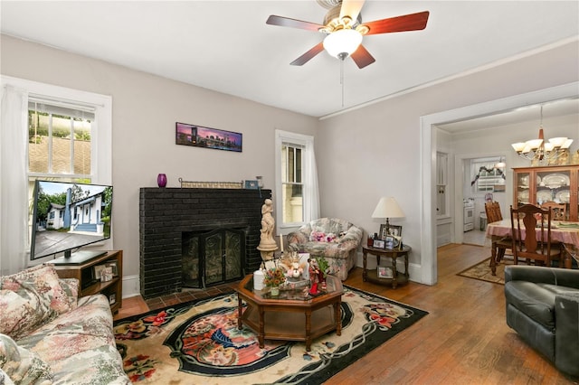 709 Daphne Ave, Umatilla, FL 32784 - living area featuring a chandelier, a fireplace, wood finished floors, and a ceiling fan