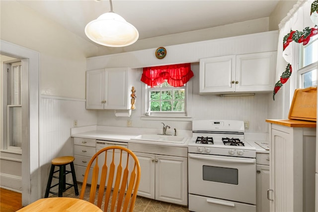709 Daphne Ave, Umatilla, FL 32784 - kitchen featuring white gas range, white cabinetry, dishwasher, and a wainscoted wall