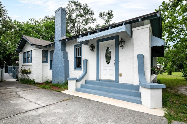 709 Daphne Ave, Umatilla, FL 32784 - view of front facade featuring entry steps, a chimney, and stucco siding