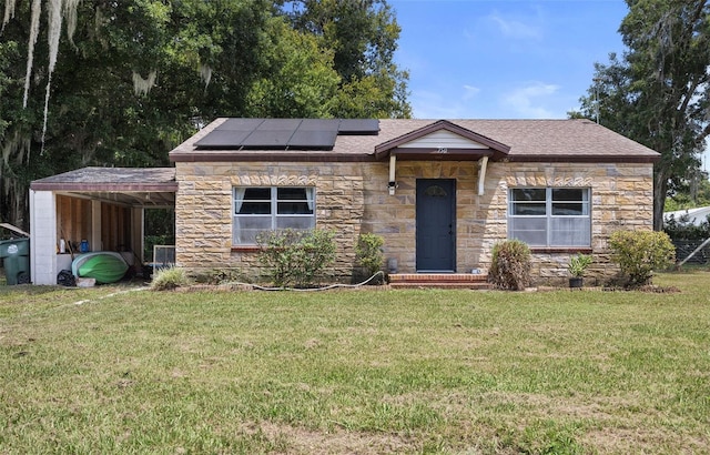750 N Kentucky Ave, Umatilla, FL 32784 - view of front facade with stone siding, a front yard, roof mounted solar panels, an attached carport, and a shingled roof
