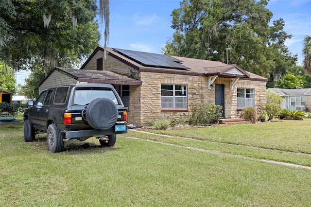 750 N Kentucky Ave, Umatilla, FL 32784 - view of front of property featuring stone siding, roof mounted solar panels, a front yard, and a shingled roof