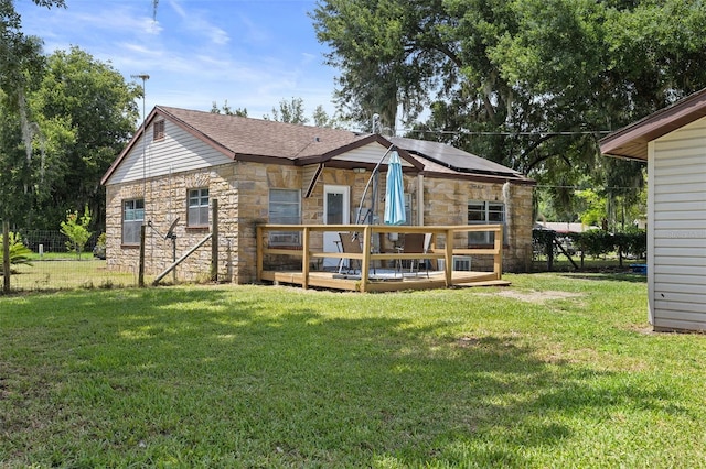 750 N Kentucky Ave, Umatilla, FL 32784 - back of property featuring stone siding, a deck, a lawn, solar panels, and a shingled roof