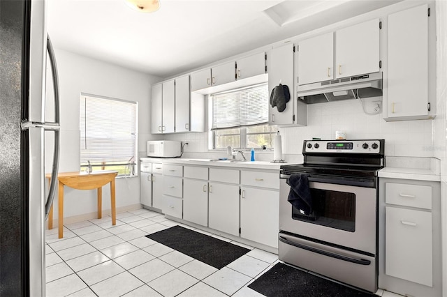 750 N Kentucky Ave, Umatilla, FL 32784 - kitchen with freestanding refrigerator, stainless steel range with electric cooktop, under cabinet range hood, tasteful backsplash, and light countertops
