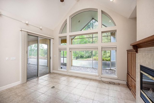 unfurnished living room with a tile fireplace, high vaulted ceiling, and light tile floors