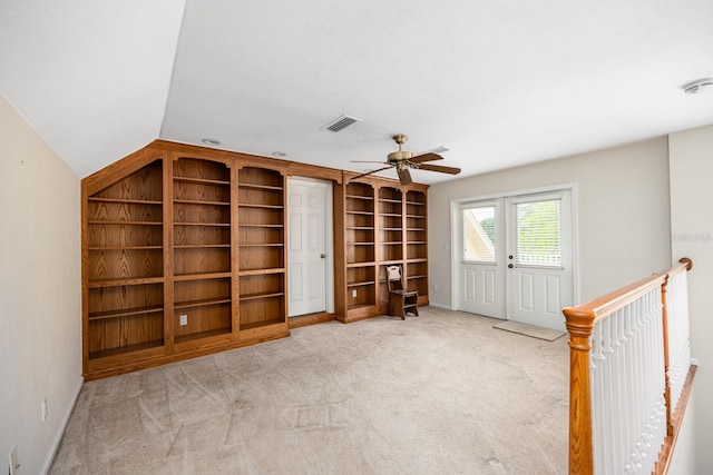 unfurnished room with built in shelves, light carpet, ceiling fan, and vaulted ceiling