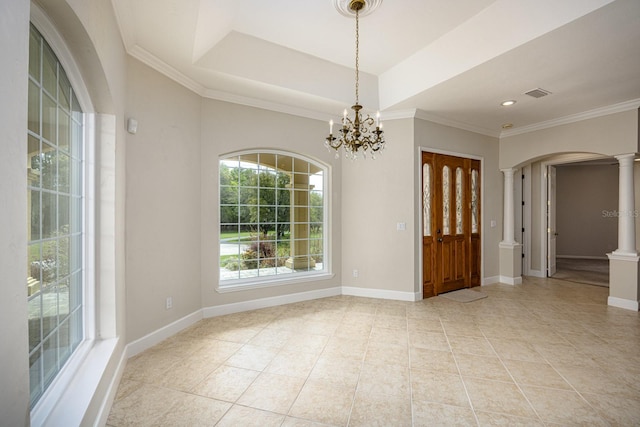 tiled empty room featuring a chandelier, ornamental molding, ornate columns, and a tray ceiling